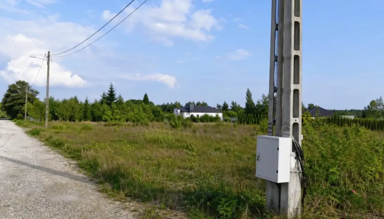 Słup energetyczny z rozdzielnicą i liniami napowietrznymi, typowe dla krajobrazu wiejskiego. Różne rodzaje linii energetycznych w tle.