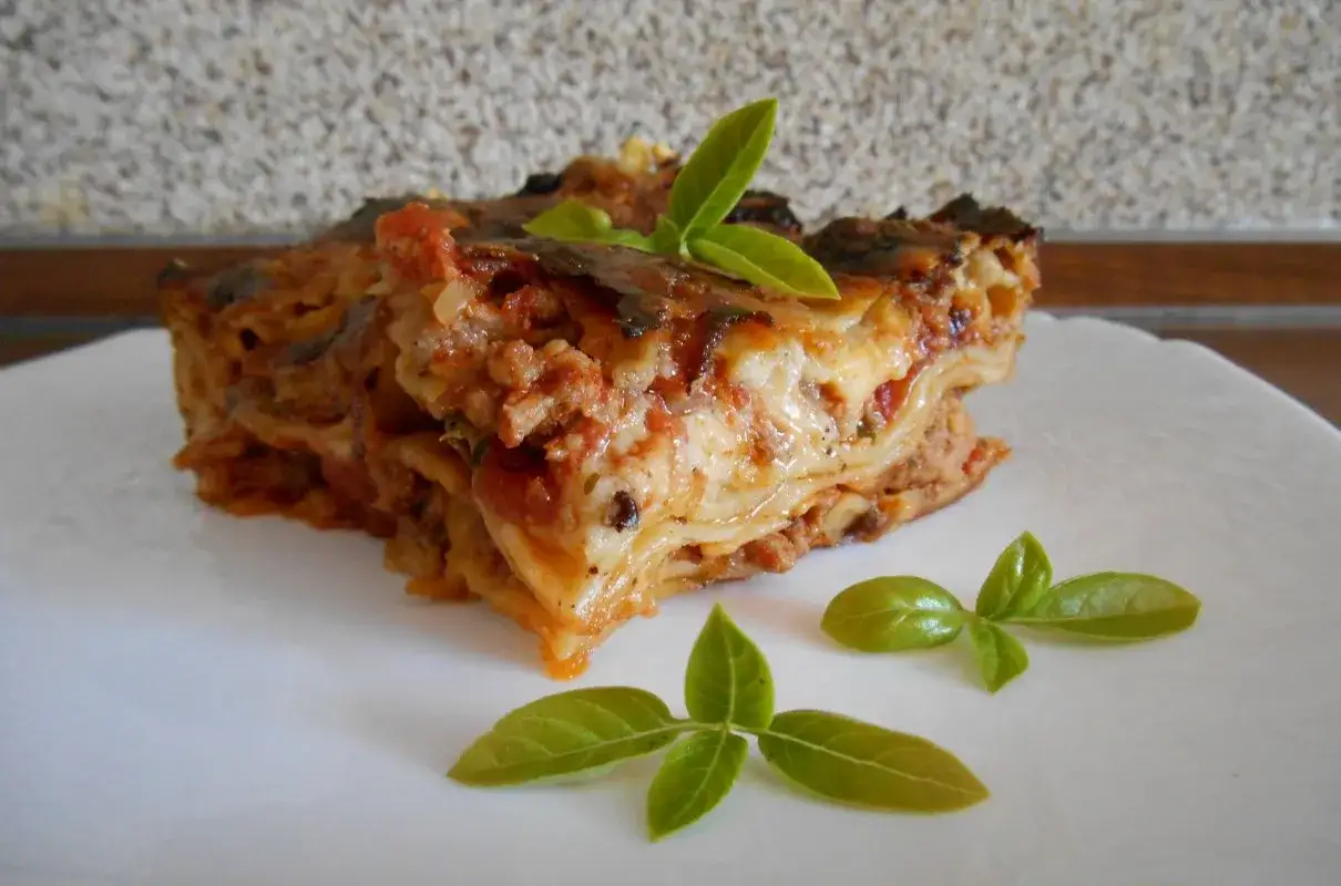 Pyszna, warstwowa lasagne z mięsem i sosem pomidorowym, ozdobiona listkami bazylii. Idealny przykład, jak zrobić lasagne.