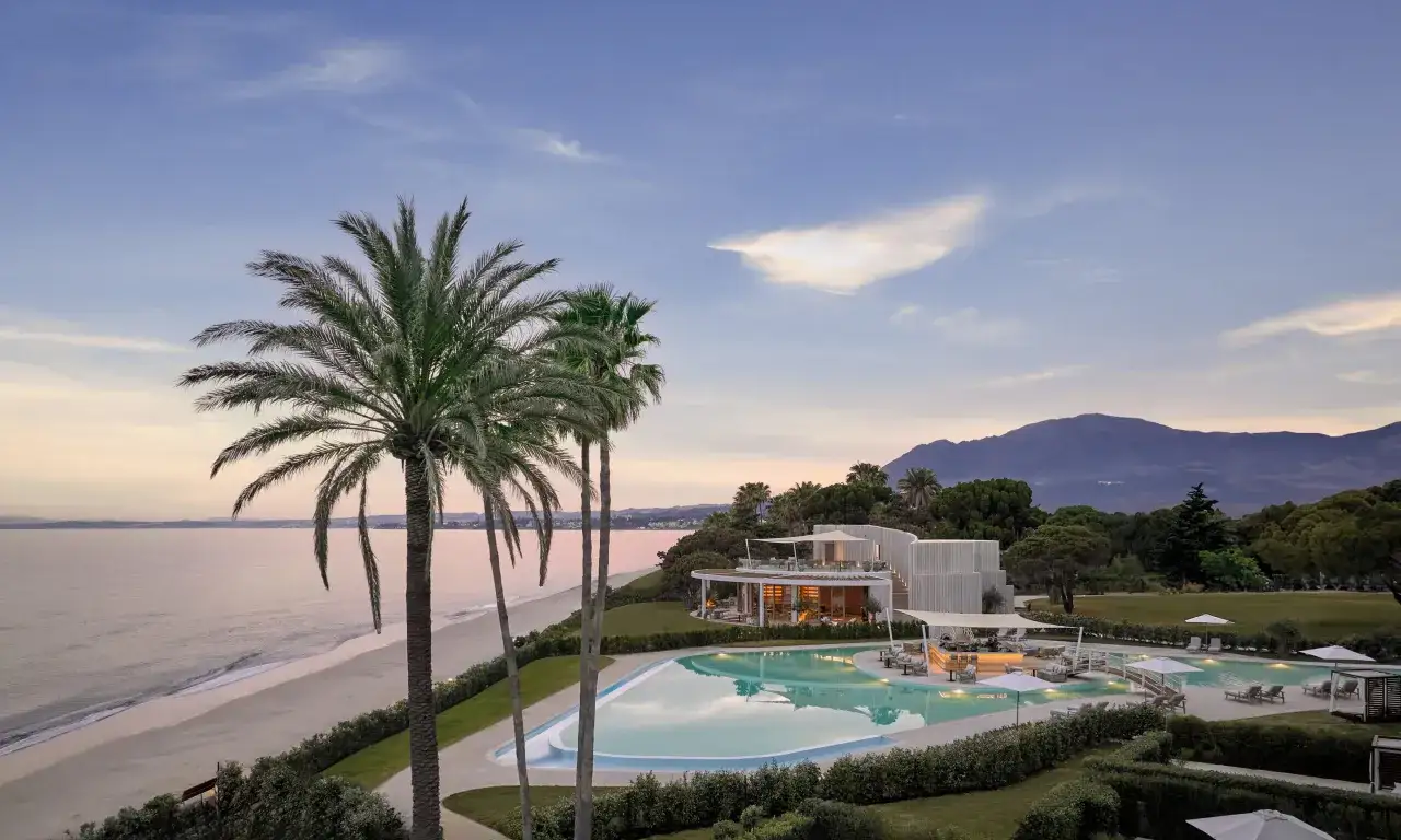 Zachód słońca nad marbella beach. Palmy, basen i góry w tle tworzą idylliczny krajobraz.
