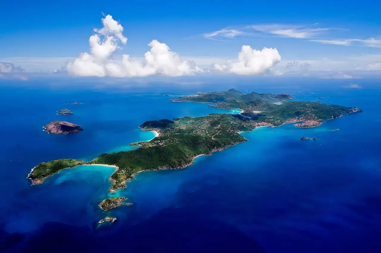 Vue aérienne de Saint-Barthélemy, île verdoyante aux plages de sable blanc baignée par des eaux bleues turquoise.