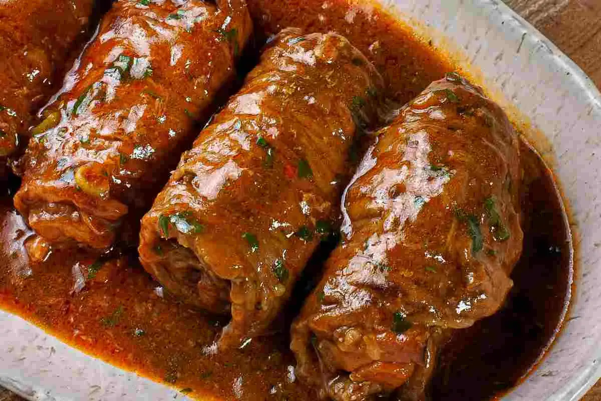 Involtini di carne in padella, succulenti e profumati, immersi in un ricco sughetto con erbe aromatiche.