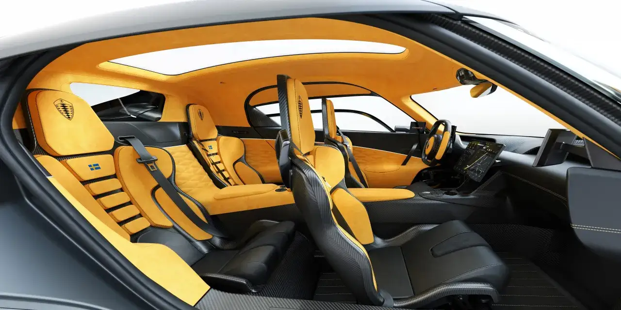 Wnętrze Koenigsegg 4 osobowy z żółtą tapicerką i czarnymi akcentami. Widoczne fotele, deska rozdzielcza i dach panoramiczny.
