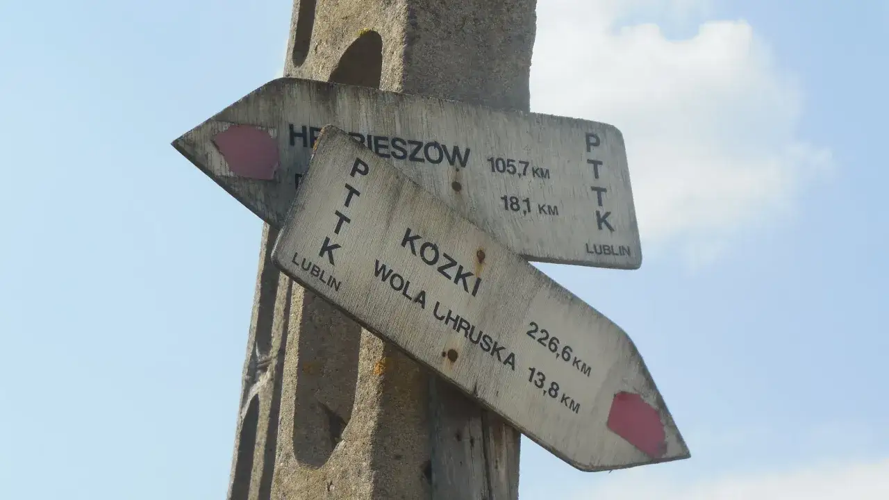Drewniane drogowskazy PTTK wskazują trasy trekkingowe do Rzeszowa, Koziek i Woli Chruskiej.