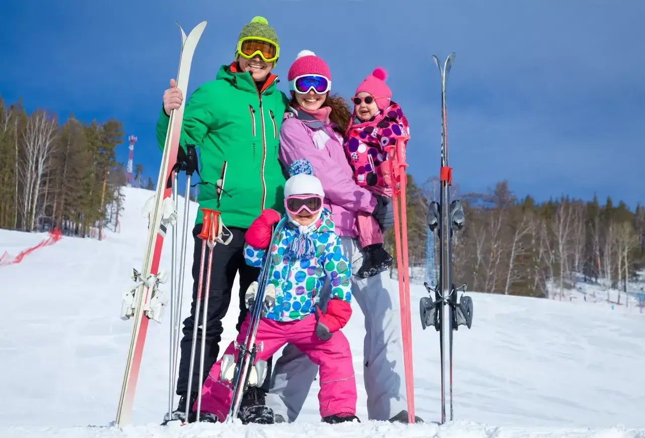 Rodzina w narciarskim stroju pozuje na tle stoku w ski centrum Strachán. Radosne dzieci i rodzice gotowi na zimowe szaleństwo.