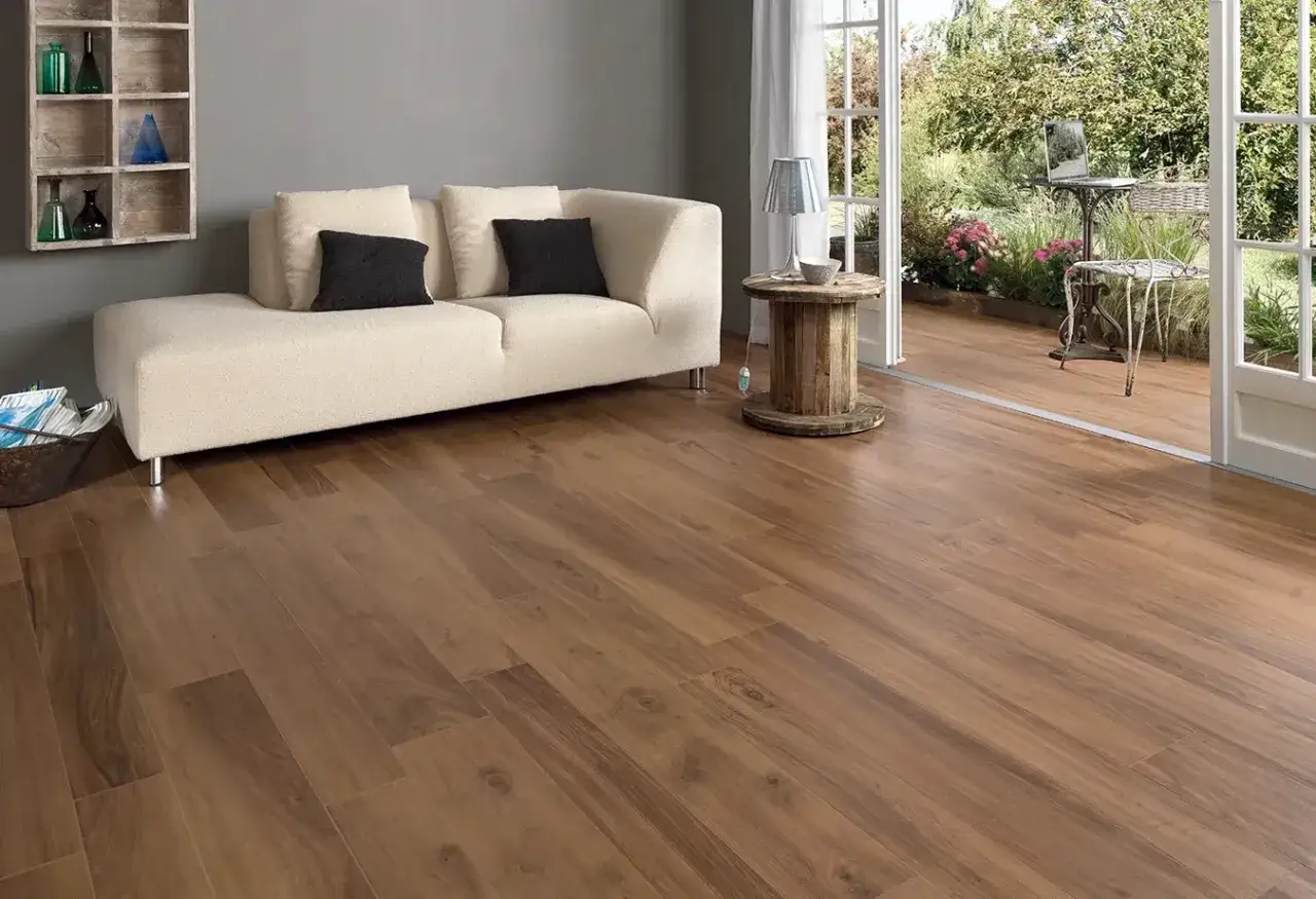 Un soggiorno moderno con divano bianco e **domus pavimenti** effetto legno che si estendono verso un giardino lussureggiante.