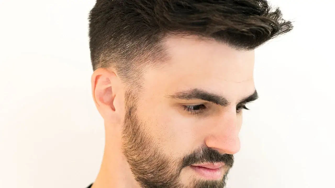 Un hombre con barba y un corte de pelo moderno, ejemplo de cortes de pelo hombre elegante.