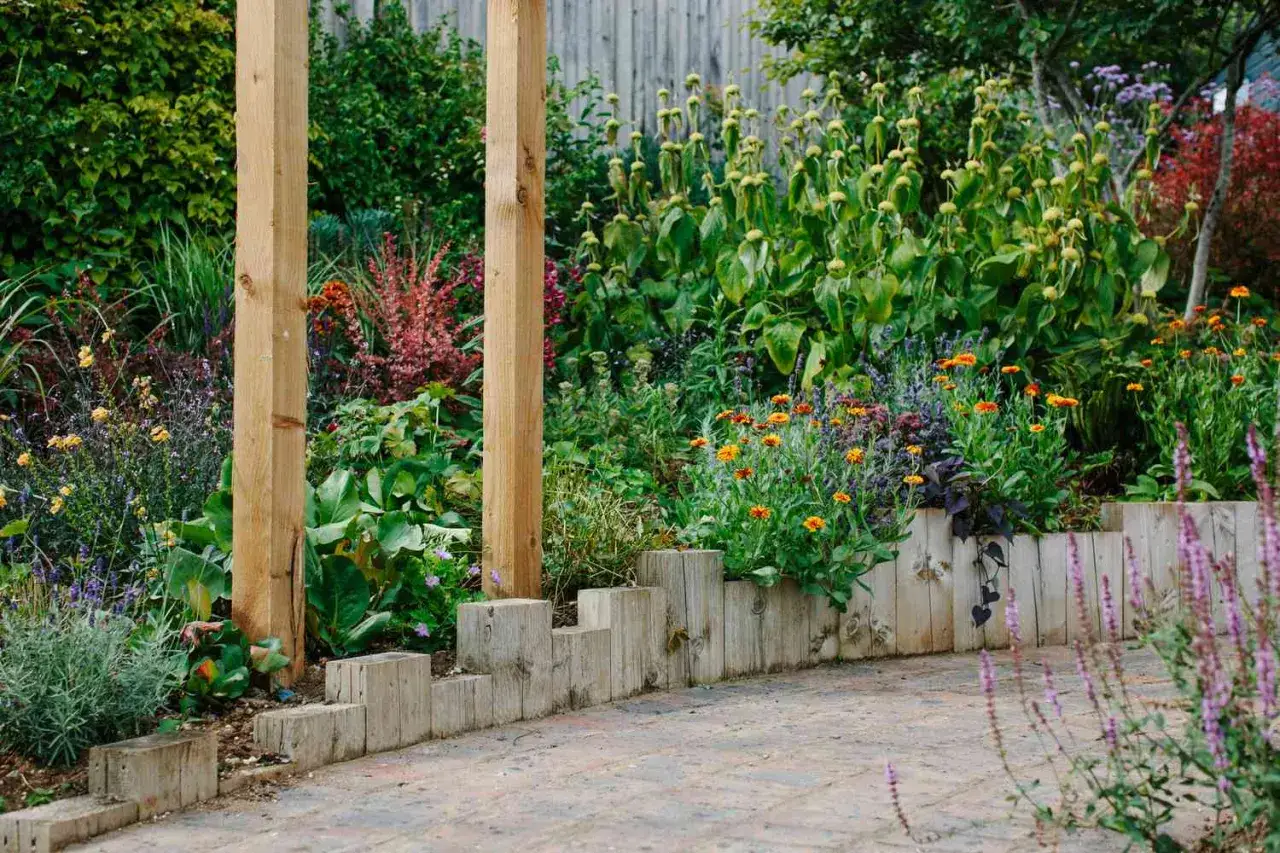Rustic wooden log border with vibrant flowers, showcasing creative landscape border ideas.