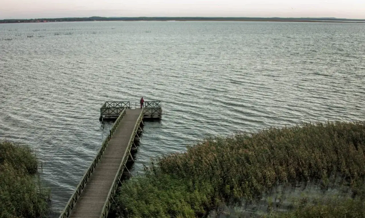 Drewniany pomost na jeziorze Łebsko, z samotną postacią na końcu. To jedna z atrakcji tego miejsca.