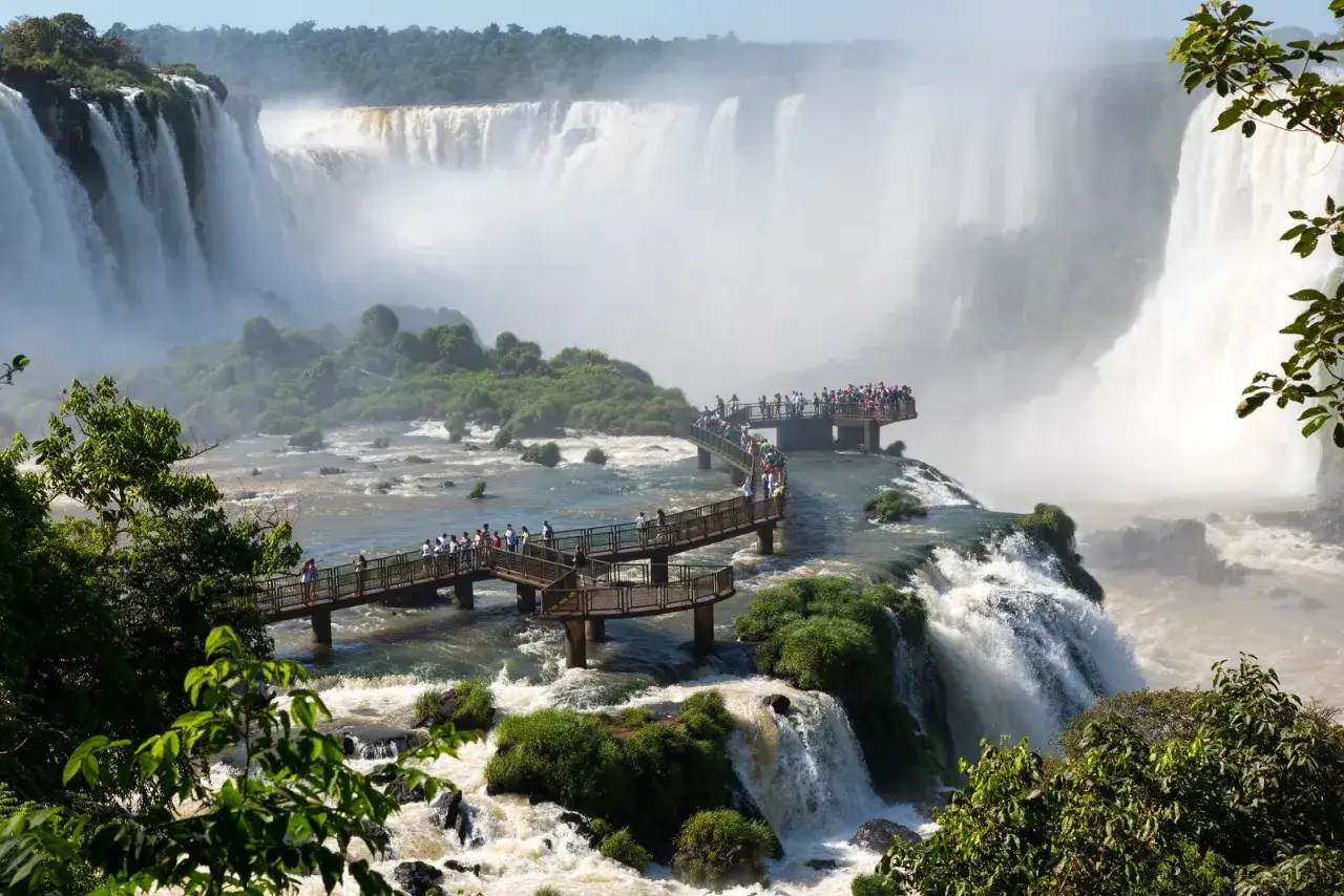 A breathtaking view of Iguazu Falls, with tourists on walkways enjoying the spectacle. A perfect memory from 2 days in Iguazu Falls.