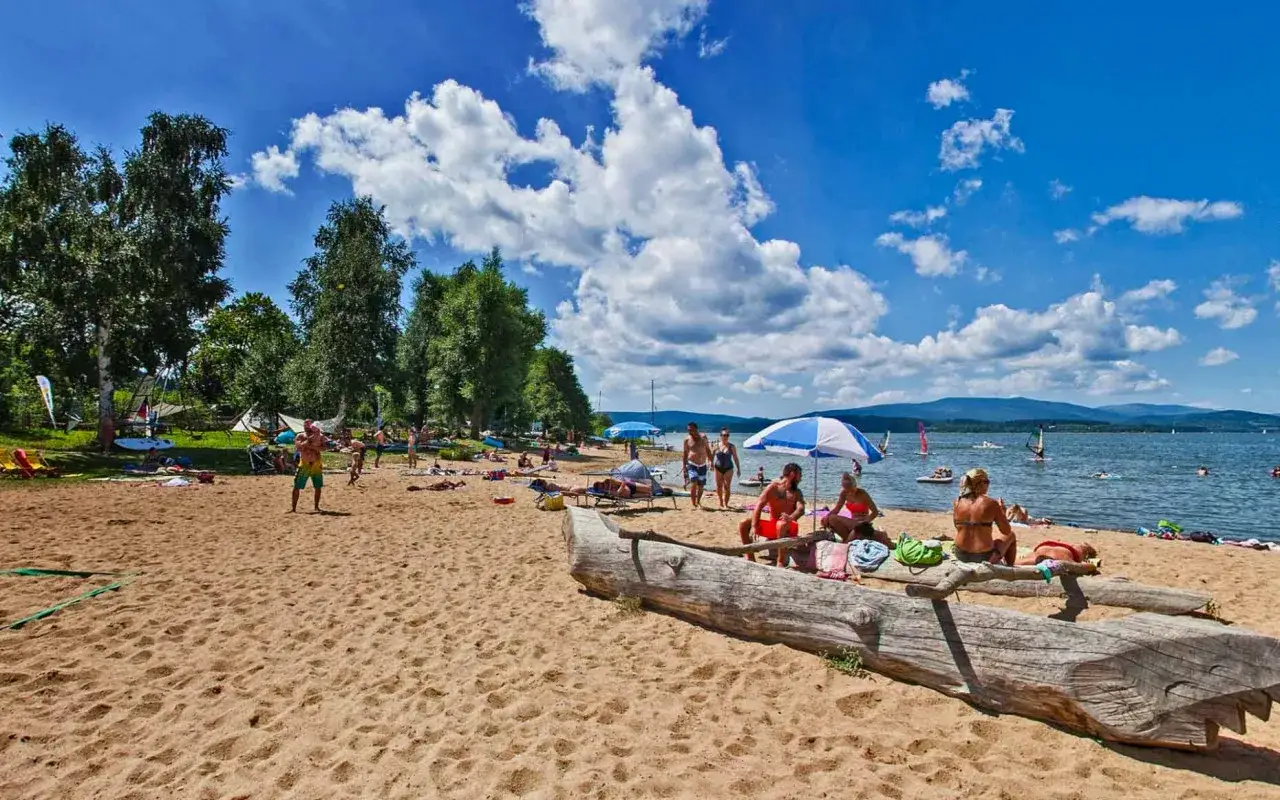 Sonniger Strand am Moldau Stausee mit vielen Badeg&auml;sten, Seglern und Windsurfern.