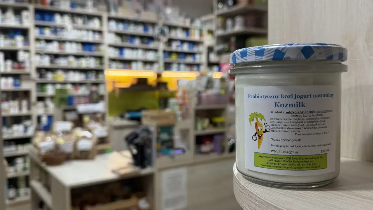 Słoik jogurtu koziego Kozmilk, idealny dla kobiet w ciąży, stoi na półce sklepu ekologicznego.