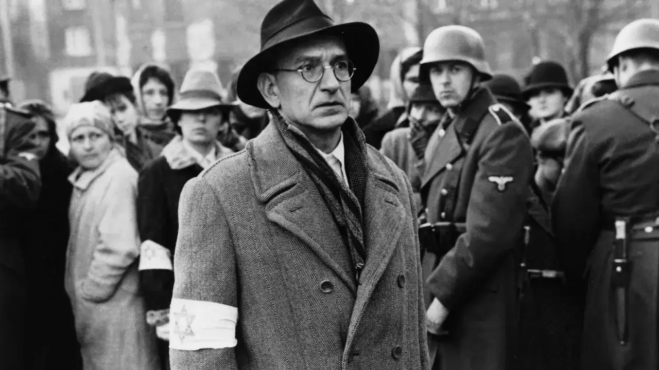 Oskar Schindler w otoczeniu ludzi, w tym żołnierzy niemieckich. Scena z filmu