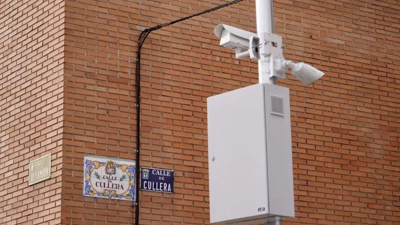Cámaras de vigilancia y señalización de calles en una pared de ladrillos, parte de una feria de seguridad.