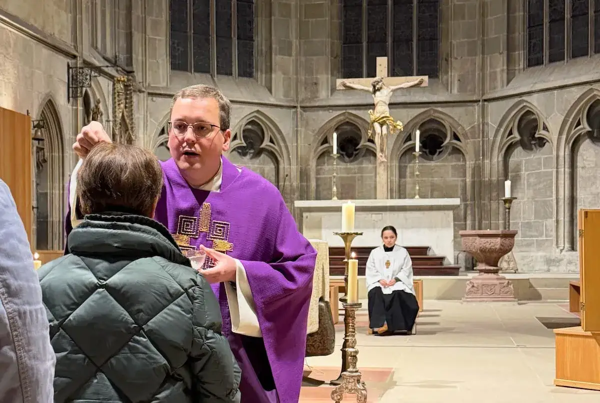Priester spendet Gläubigen Asche auf die Stirn. Dies erinnert daran, was fastet man in der Fastenzeit: Verzicht und Besinnung.