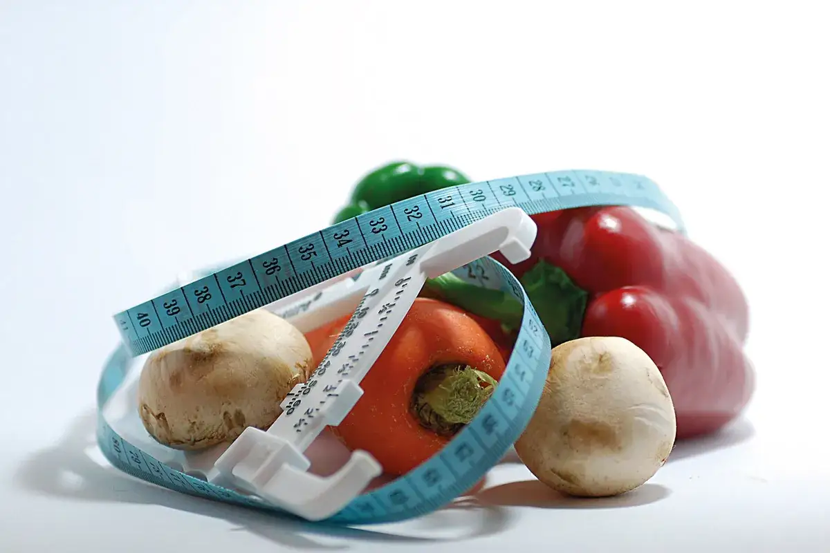 Verduras frescas y cinta m&eacute;trica, s&iacute;mbolos de dietas milagro.
