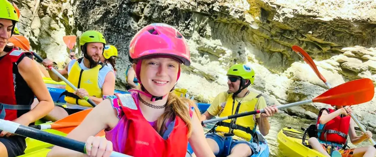 Giovani sorridenti in kayak, pronti per un'avventura di rafting nelle Marche. Caschi colorati e giubbotti di salvataggio per un'esperienza indimenticabile.