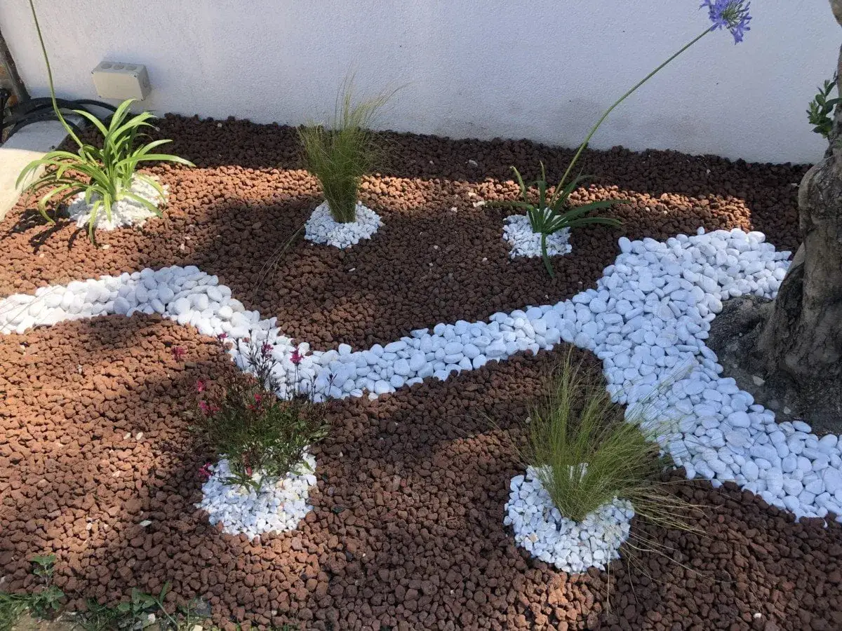 Un jardin paysager avec des pierres blanches et de la pouzzolane rouge. Ces matériaux sont parfaits pour savoir que mettre au sol pour éviter les mauvaises herbes.