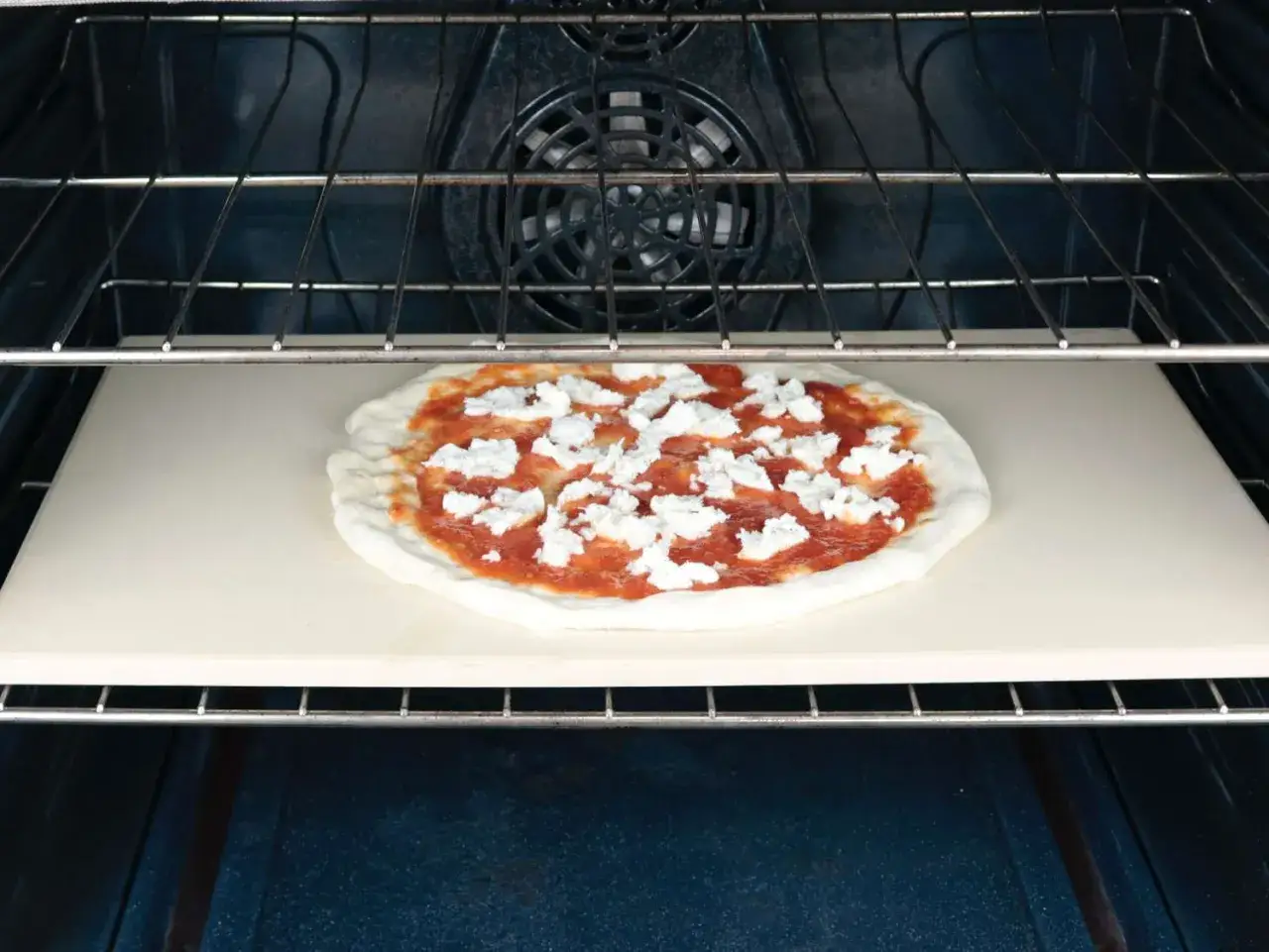 Pizza na kamieniu w piekarniku. Idealna temperatura pieczenia pizzy to klucz do chrupiącego ciasta i rozpływającego się sera.