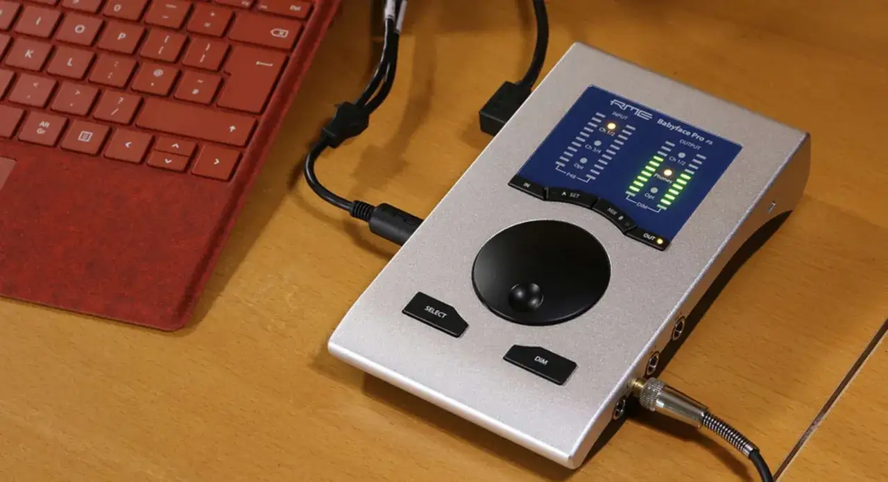 Srebrne urządzenie RME Babyface Pro FS podłączone do czerwonej klawiatury. Idealne do produkcji muzyki.