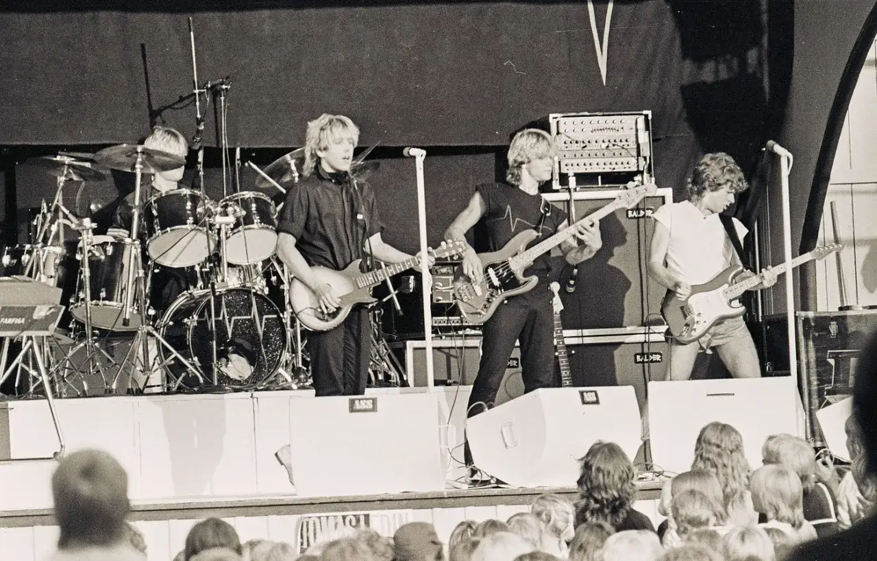 Ett svenskt dansband fr&aring;n 70-talet spelar p&aring; scen. Trummor, gitarrer och bas h&ouml;rs n&auml;r publiken njuter.