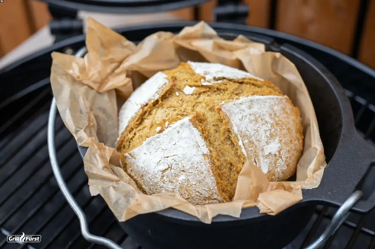 Frisch gebackenes Brot im Gusseisentopf auf dem Grill. Die richtige Temperatur beim Brot backen auf dem Gasgrill ist entscheidend für eine knusprige Kruste.