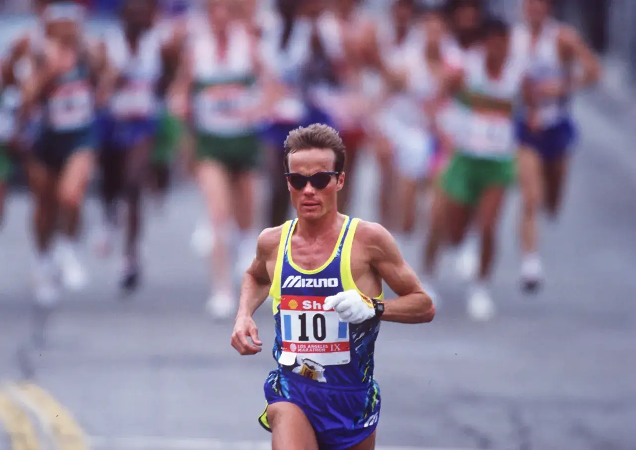 Corredor con gafas de sol y dorsal 10, concentrado en mantener su ritmo en el marat&oacute;n.