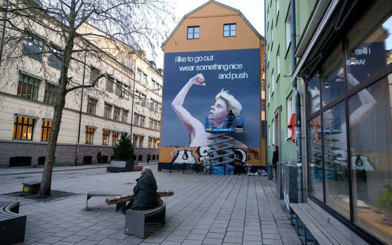 Stor muralmålning av Robyn på en byggnad. Kanske är det här Robyn bor, i en stad med vackra hus och en lugn gata.