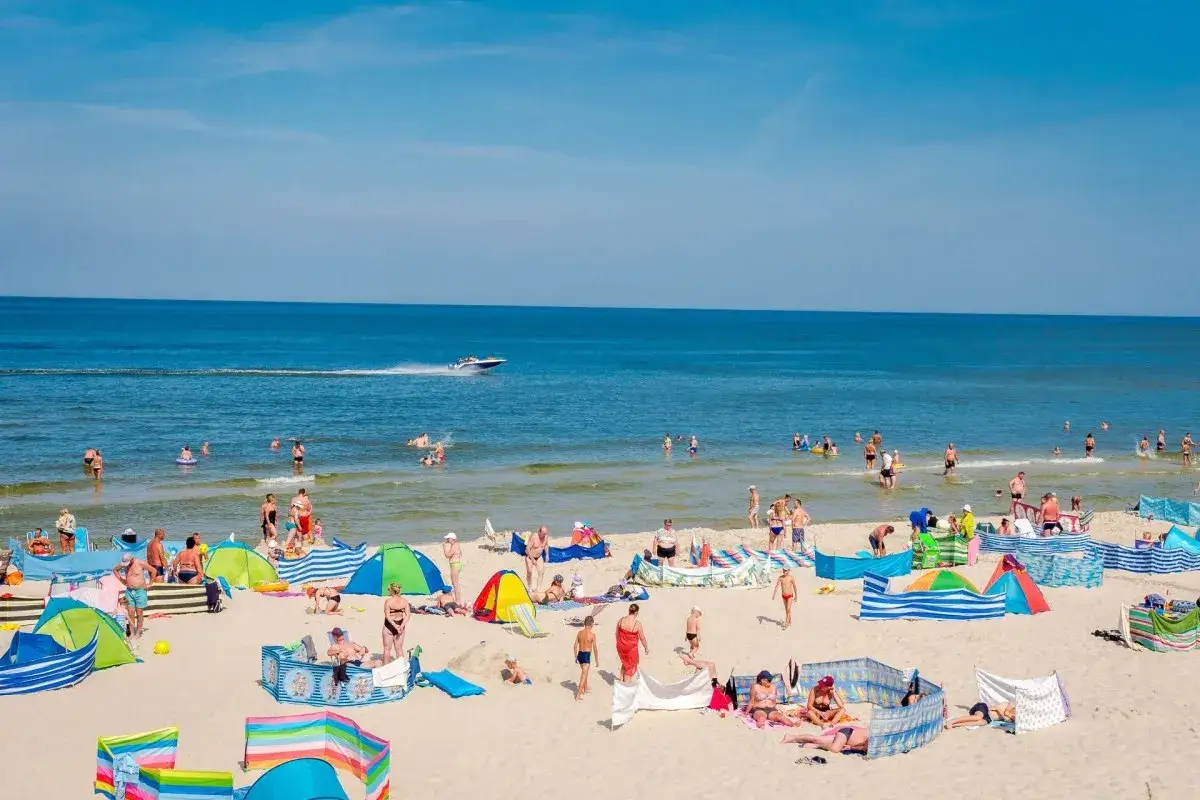Słoneczna plaża w Karwi pełna ludzi. Wiele kolorowych parawanów i namiotów. Idealne miejsce na noclegi ze śniadaniem.