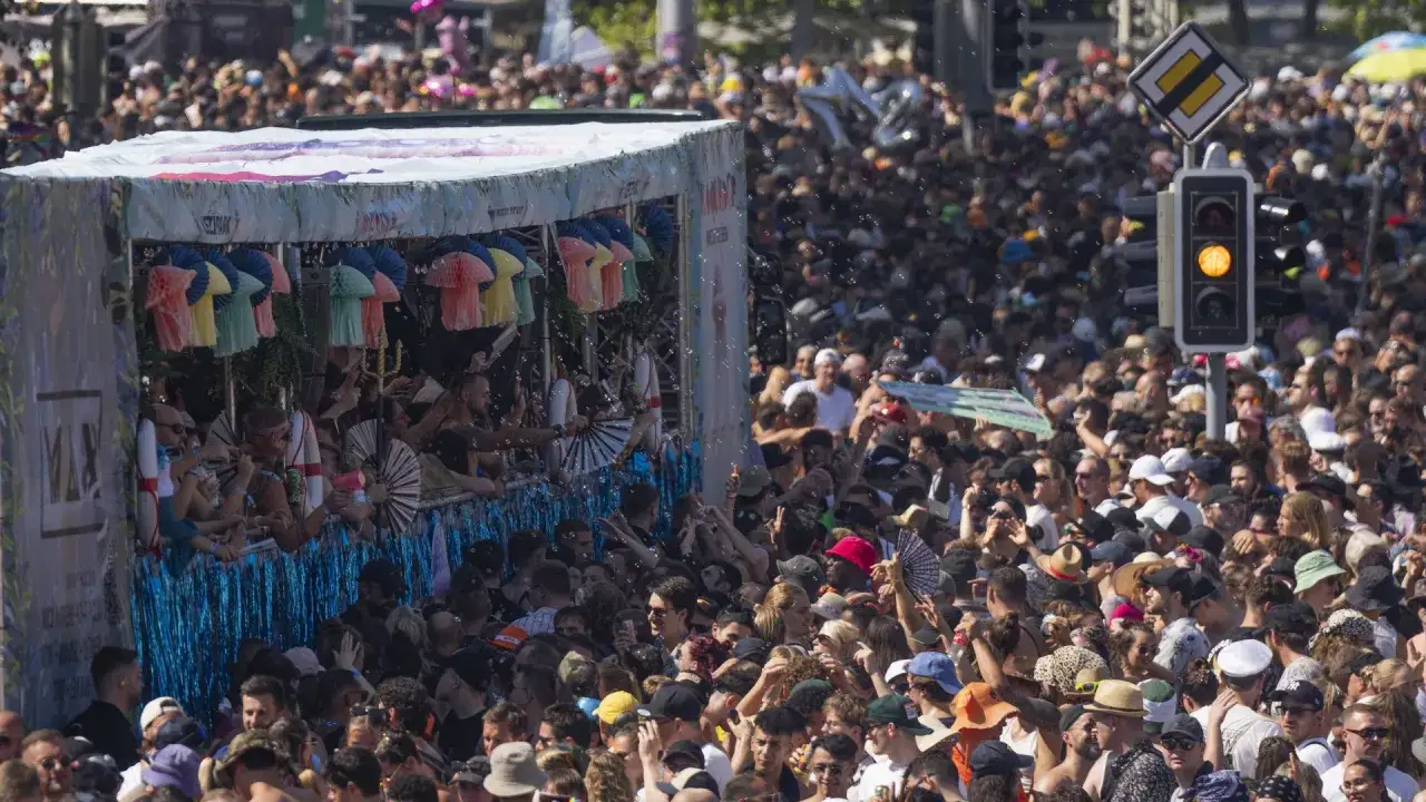 Folla festante a Zurigo durante una street parade. Persone in estasi, bolle di sapone e un carro colorato creano un'atmosfera vibrante.