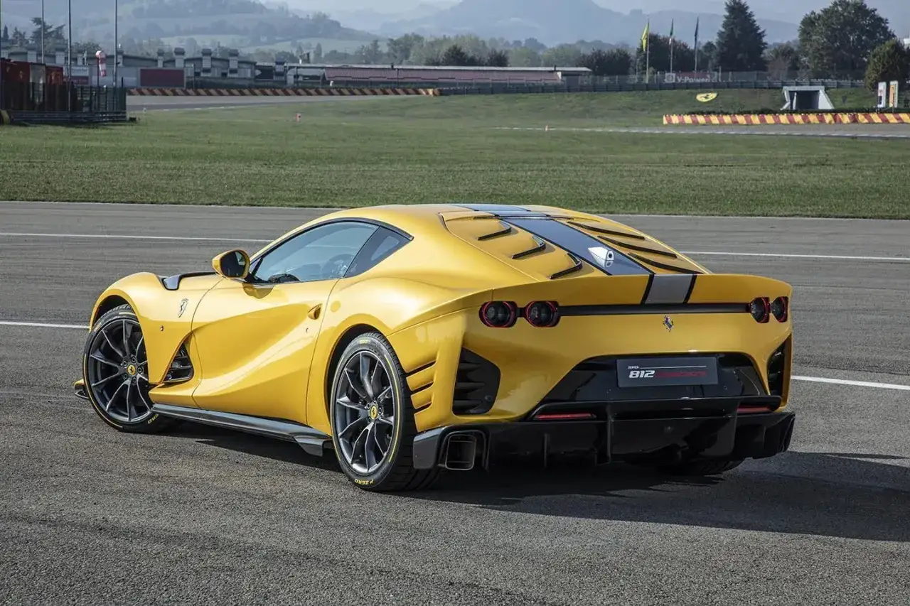 Żółte Ferrari 812 Competizione na torze wyścigowym, z widocznym dyfuzorem i podwójnymi światłami.