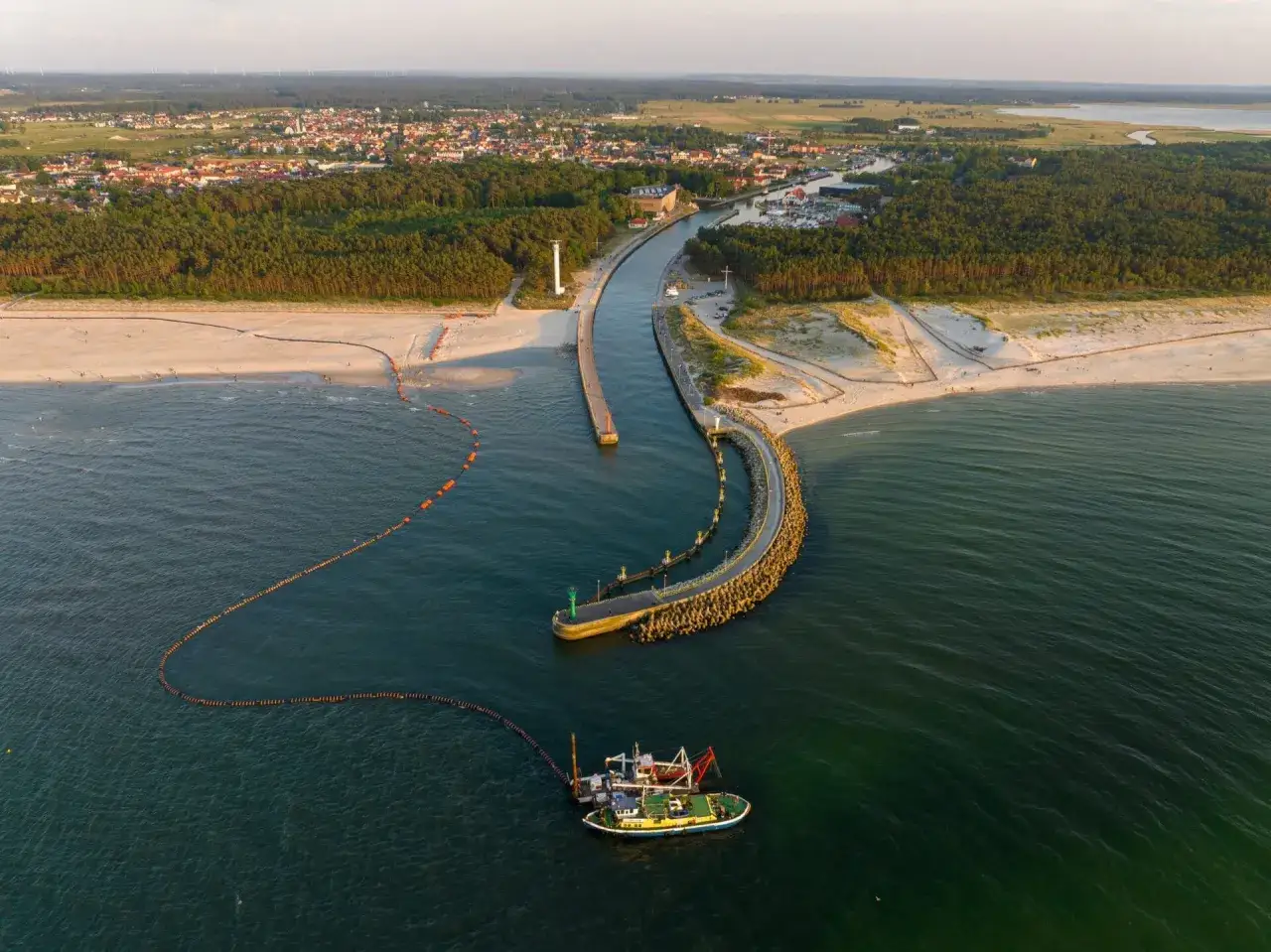 Łeba atrakcje poza sezonem: port, kanał, latarnia morska i plaża. Statek pracuje na wodzie.