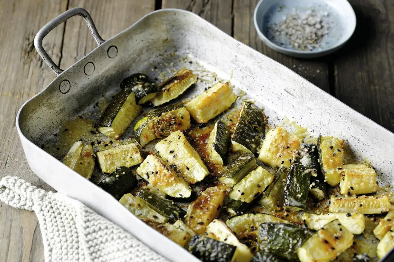 Ger&ouml;stete Zucchini-St&uuml;cke mit Sesam und Gew&uuml;rzen in einer Metallpfanne. Ein k&ouml;stliches Beispiel f&uuml;r Zucchini Rezepte, bereit zum Servieren.