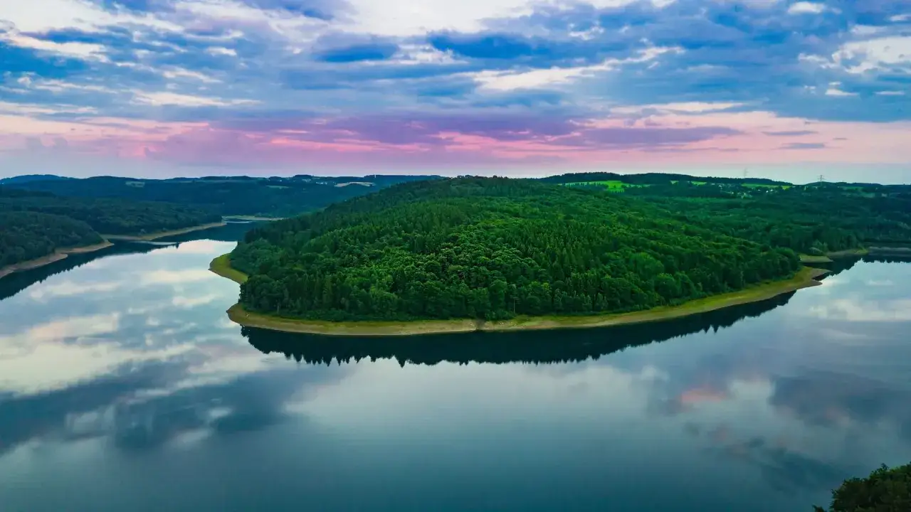 Idyllische Szene an der Wiehltalsperre mit gr&uuml;nen W&auml;ldern und spiegelglattem Wasser. Perfekt f&uuml;r Wanderwege.