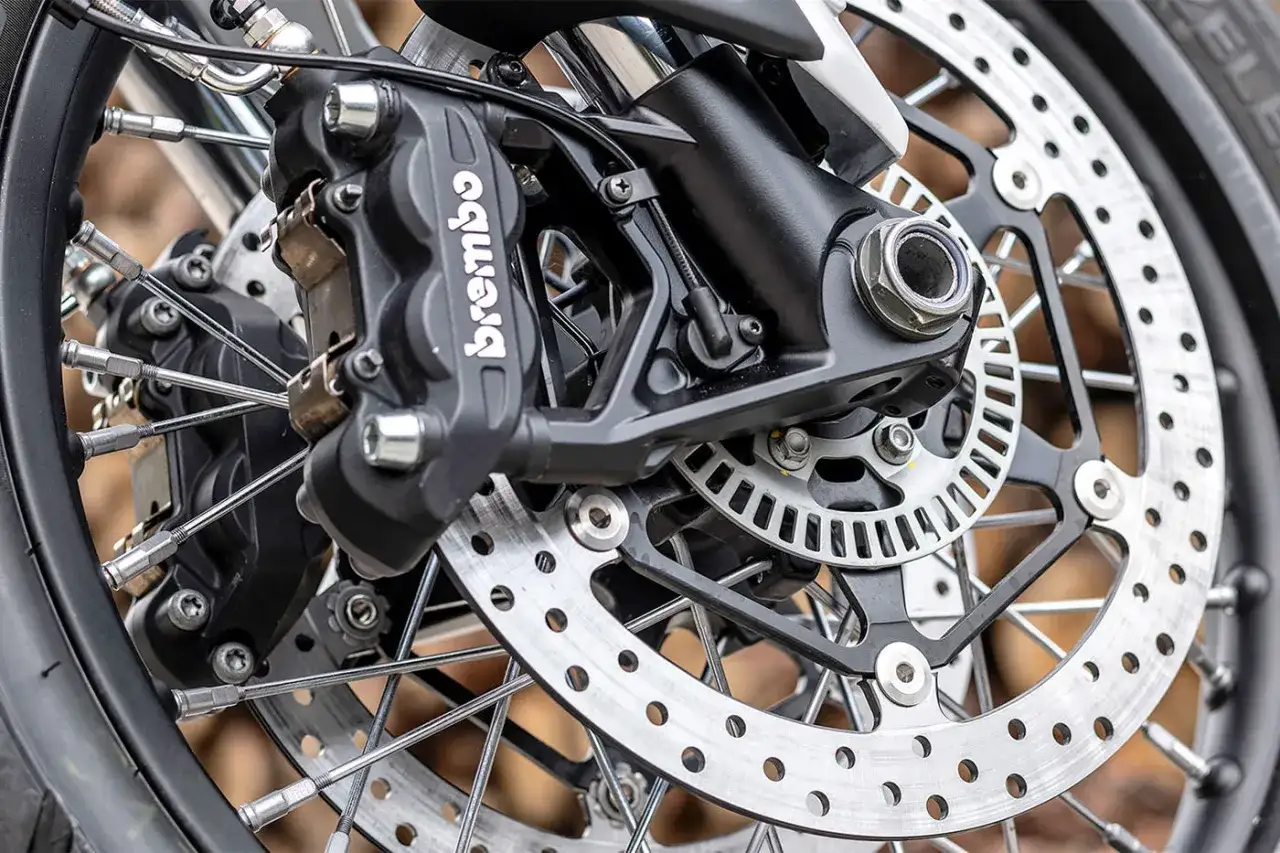 Dettaglio del sistema frenante di una moto, con pinza Brembo e disco forato. Pronto per cambiare pastiglie freni moto.