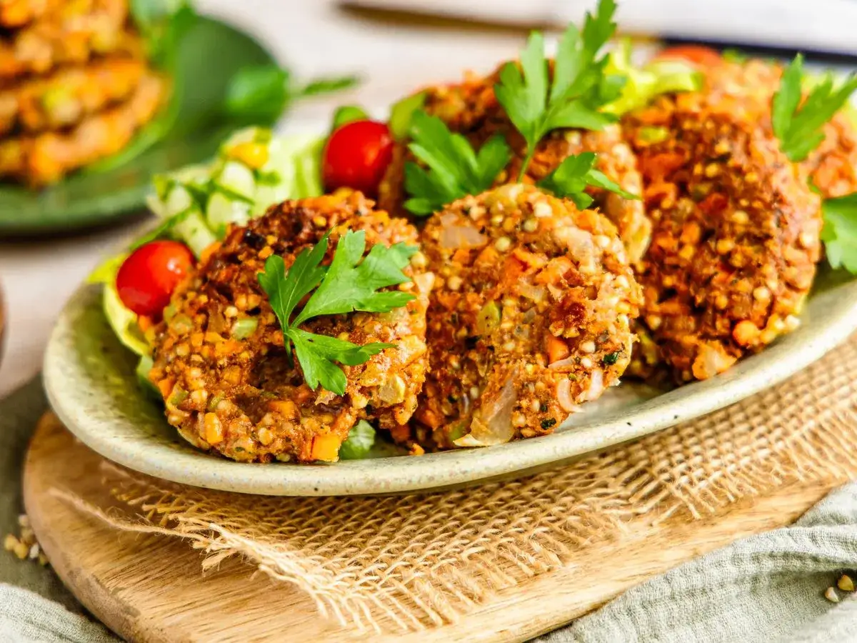 Herzhafte buchweizen bratlinge mit frischem Salat und Kirschtomaten, garniert mit Petersilie.