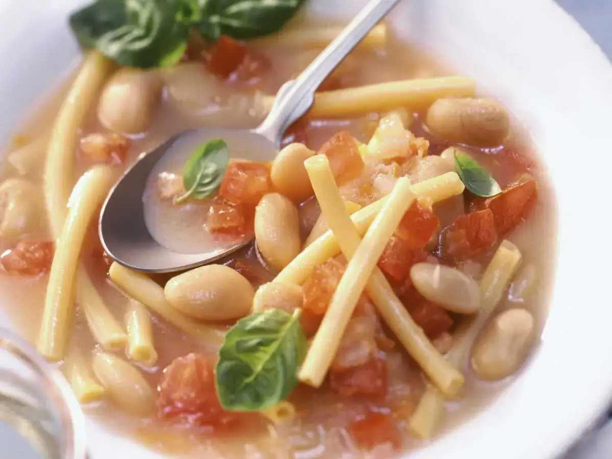 Un bol de pasta e fagioli r&eacute;confortant, garni de basilic frais. Les p&acirc;tes, haricots blancs et tomates se m&eacute;langent dans un bouillon savoureux.