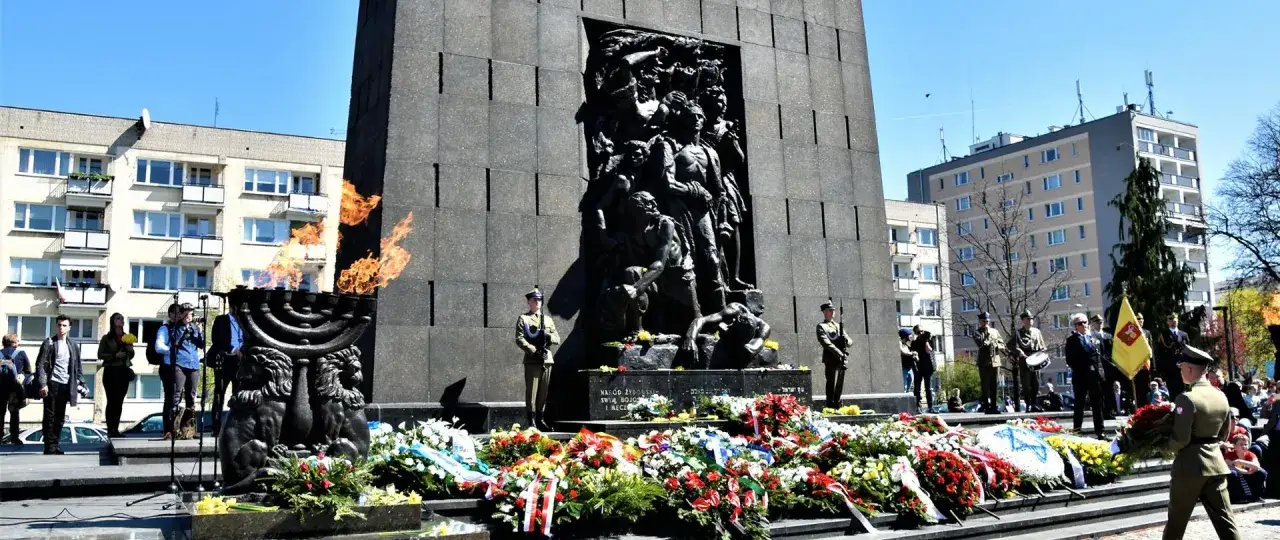 Pamięć o powstaniu w getcie warszawskim. Płonący znicz i wieńce u stóp pomnika bohaterów.