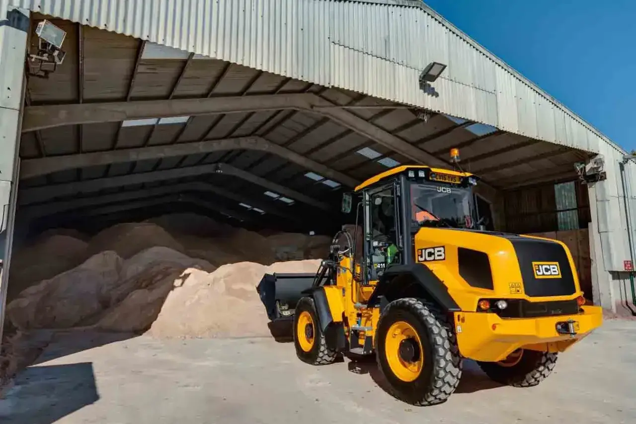Żółta ładowarka JCB 406, gotowa do pracy przy zmagazynowanym materiale. Poznaj jej jcb 406 dane techniczne.