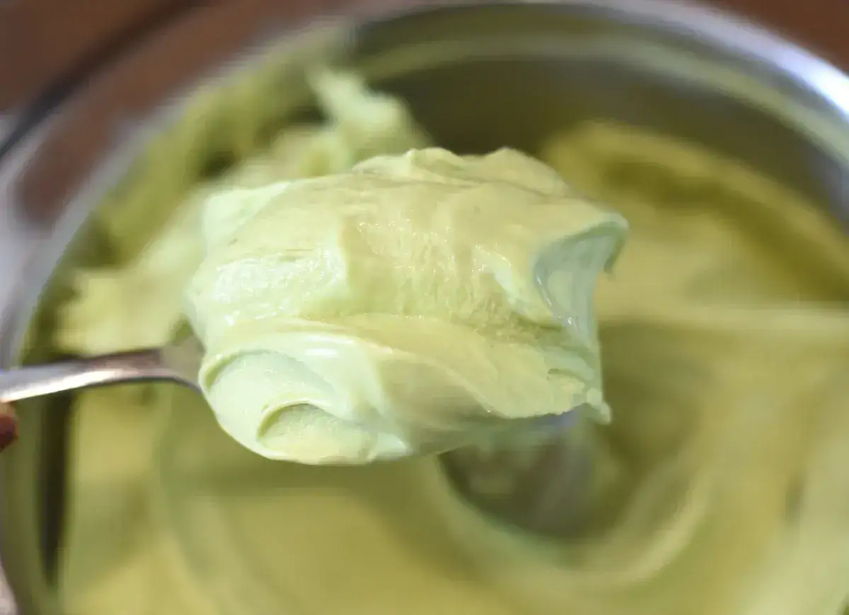 Łyżka nakłada krem pistacjowy z mascarpone. Delikatna, zielona masa rozpływa się na łyżce, zapowiadając deserowe doznania.