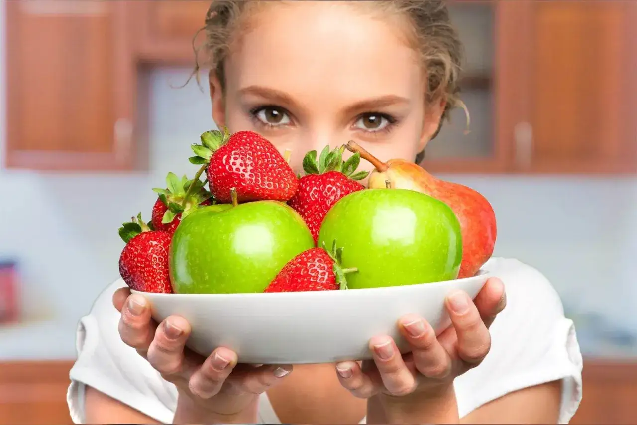 Post Daniela Zasady: miska pełna świeżych jabłek, truskawek i gruszek, prezentująca zdrowe odżywianie.