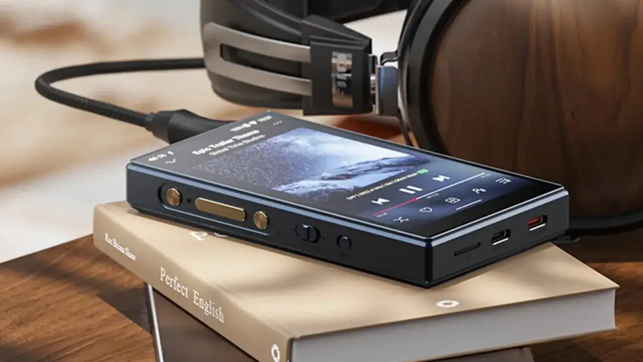 Un reproductor mp3 android con pantalla táctil, conectado a unos auriculares de alta gama, descansa sobre libros.