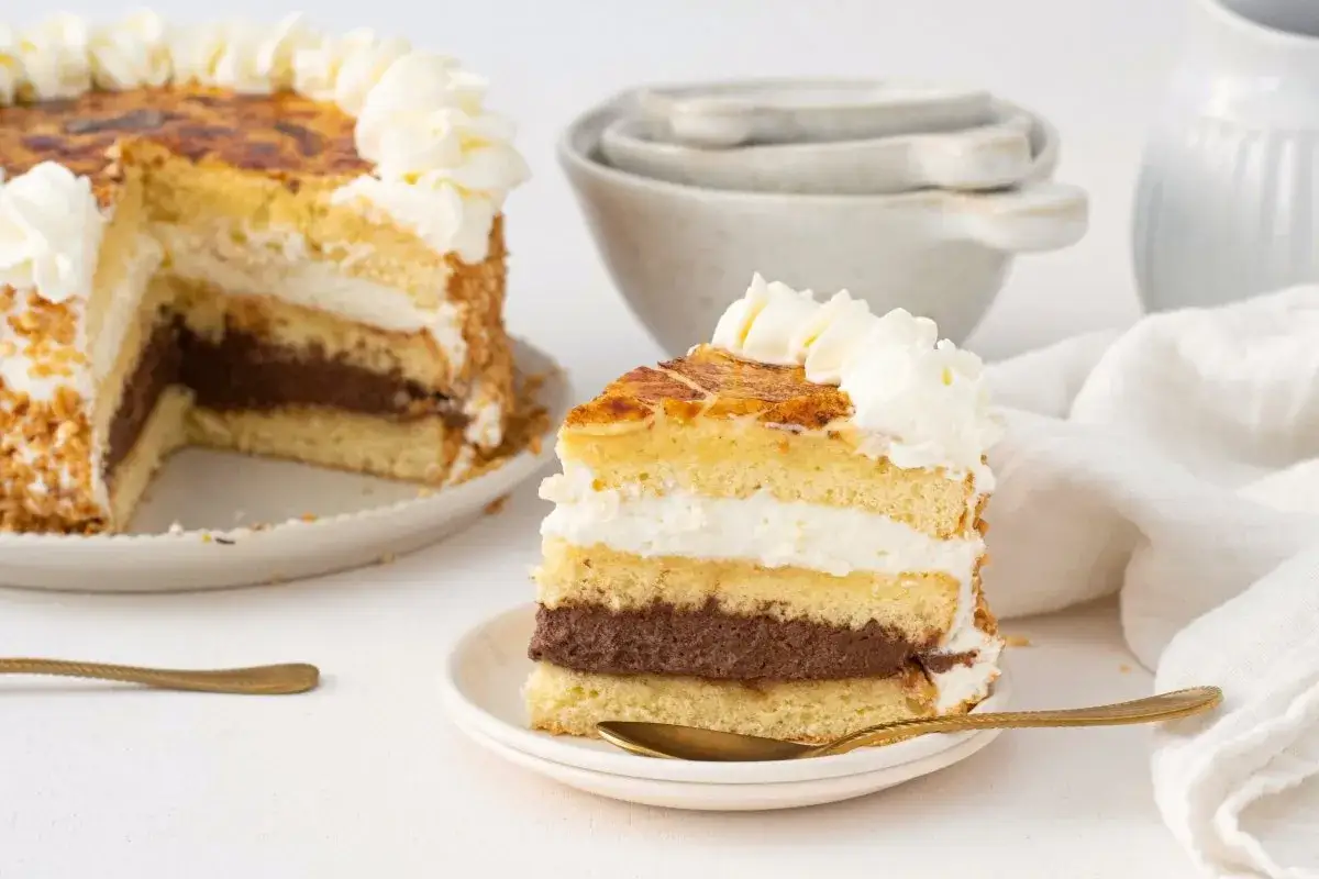 Tarta San Marcos con capas de bizcocho, crema de chocolate y nata, coronada con caramelo tostado.