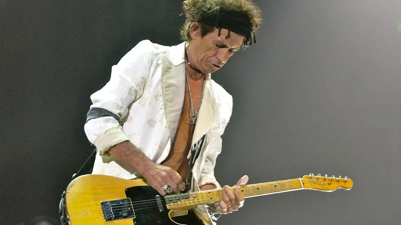 Keith Richards suona la sua iconica Telecaster con un blazer bianco ricamato, un vero rocker sul palco.
