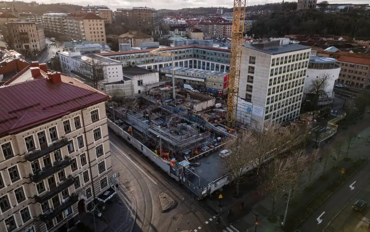 Byggarbetsplats med kran och byggnader. En skylt p&aring; ett hus antyder att det r&ouml;r sig om en serneke konkurs.