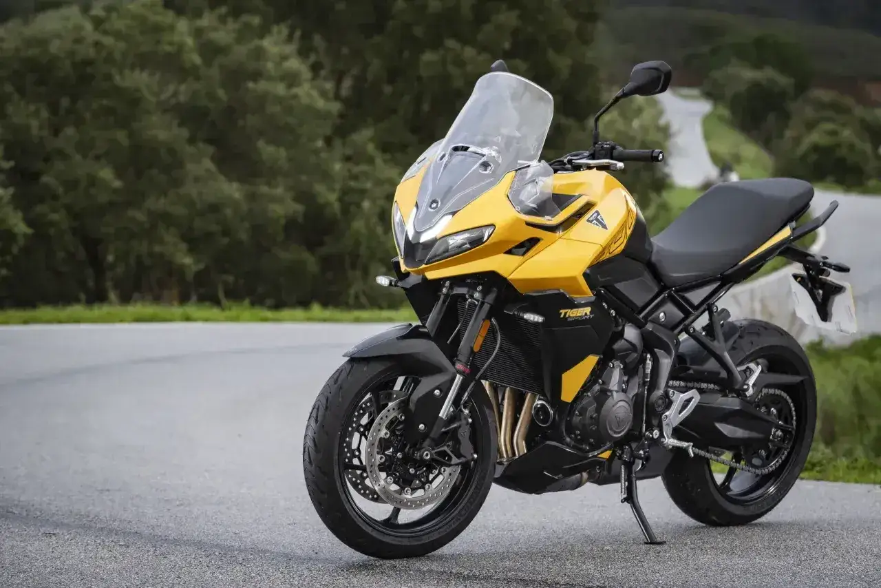 Żółty motocykl Triumph Tiger Sport na drodze. Chcesz wiedzieć, jak odpalić motocykl po długim postoju? Sprawdź instrukcję!
