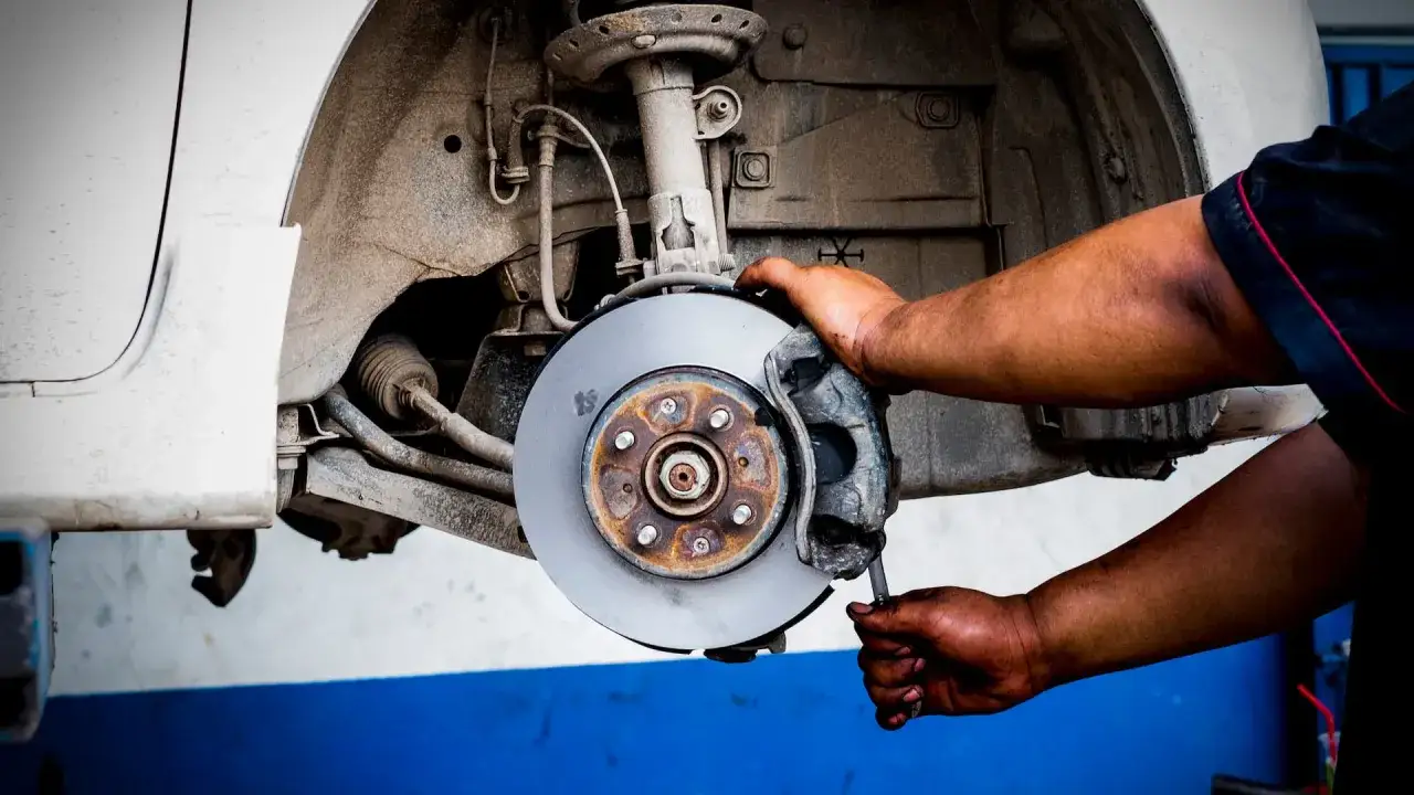 Mechaniker arbeitet an Bremsscheibe. Bald werden die Bremsen quietschen ohne zu bremsen, wenn sie nicht richtig repariert werden.