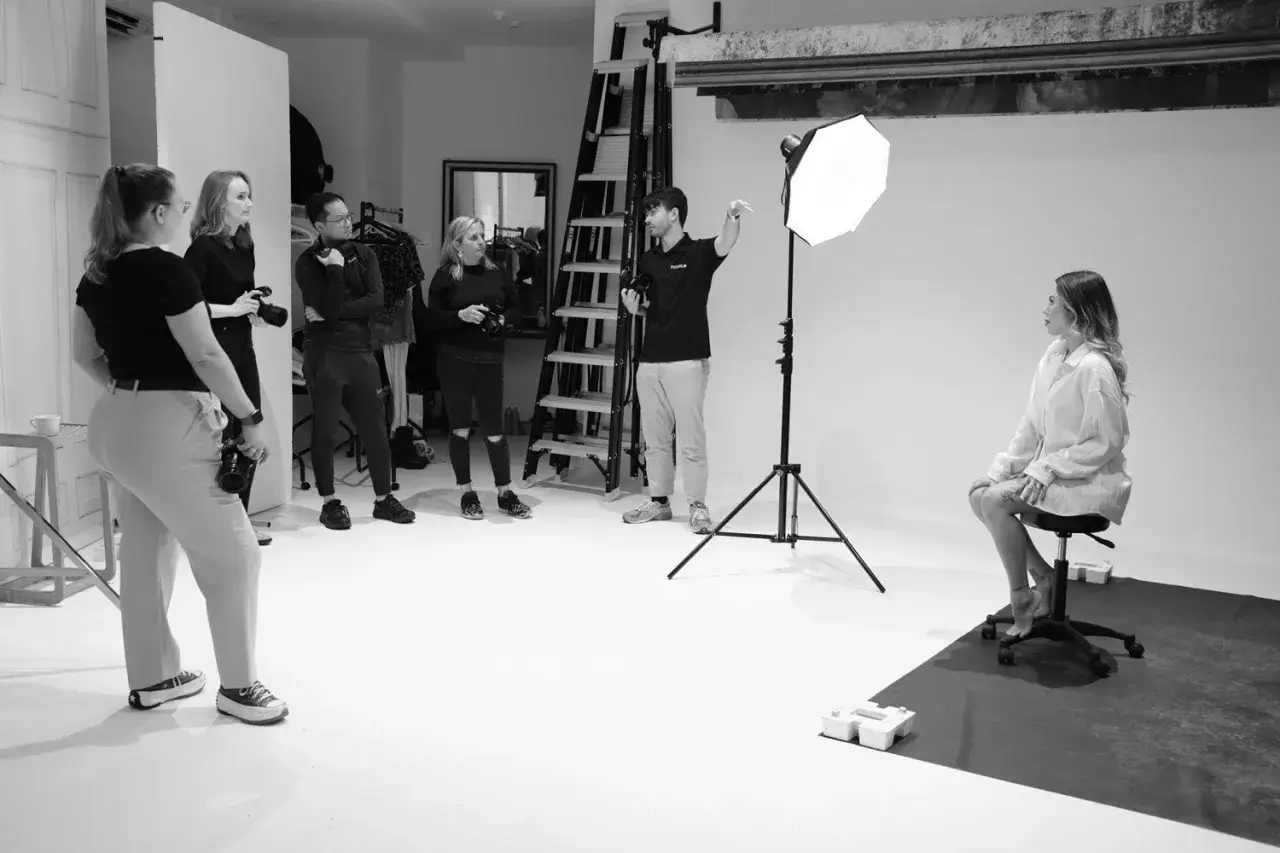 Grupa fotografów z aparatami, w tym Fuji X H2, obserwuje sesję zdjęciową modelki.