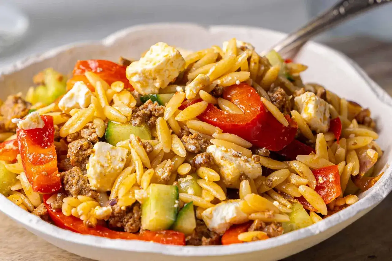 Herzhafter Kritharaki Salat mit Hackfleisch, Feta, Gurke und roten Paprikastücken. Ein köstliches Gericht, das alle Geschmacksnerven verwöhnt.