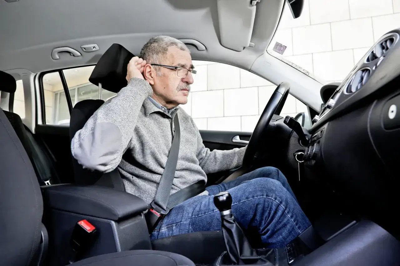 Starszy mężczyzna w samochodzie, trzymający się za ucho, zaniepokojony. Wciskam gaz, obroty rosną, a auto nie przyspiesza.