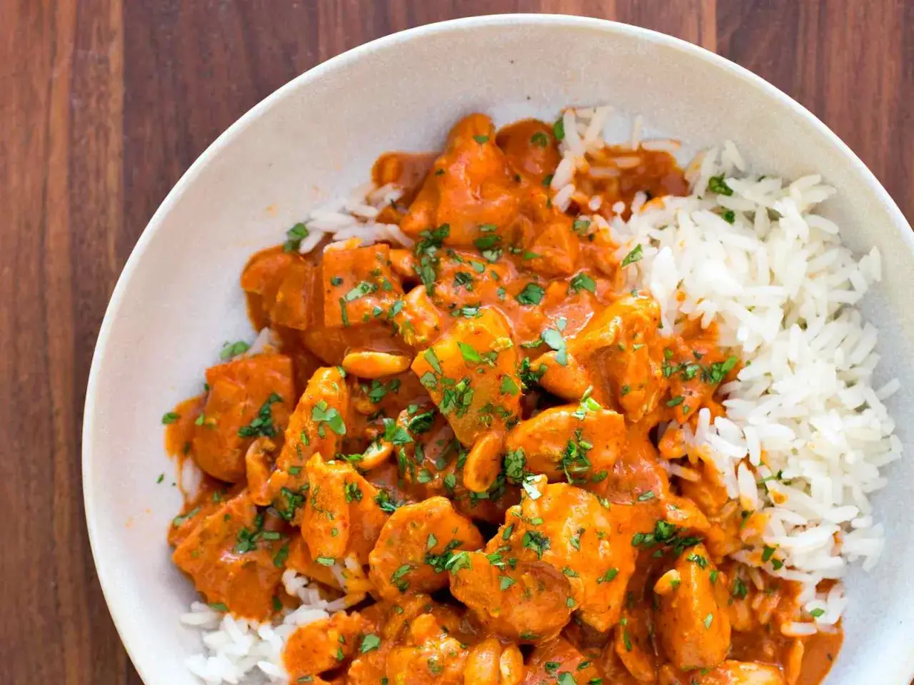 En skål med kyckling massaman curry och ris, toppad med färsk koriander.